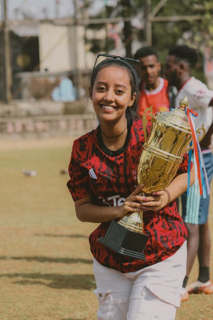 A joyful teenager holding a trophy outdoors, symbolizing victory and achievement.