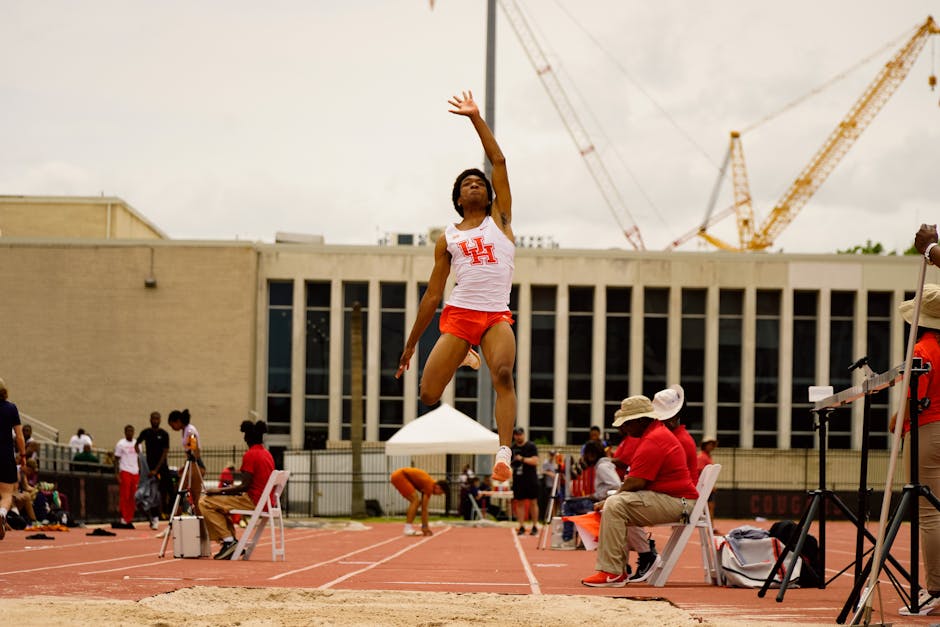 Male athlete performing a long jump at a track event in Houston, TX, showcasing athleticism and determination.