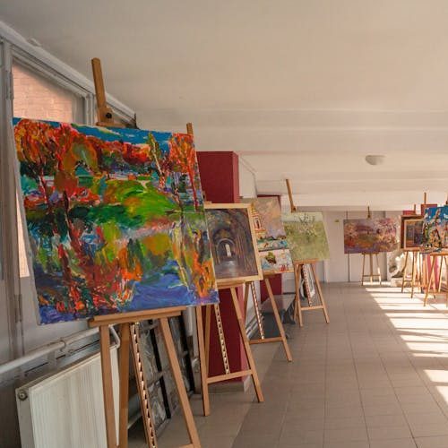 Colorful paintings displayed in a sunlit art academy corridor in Kyiv, Ukraine.